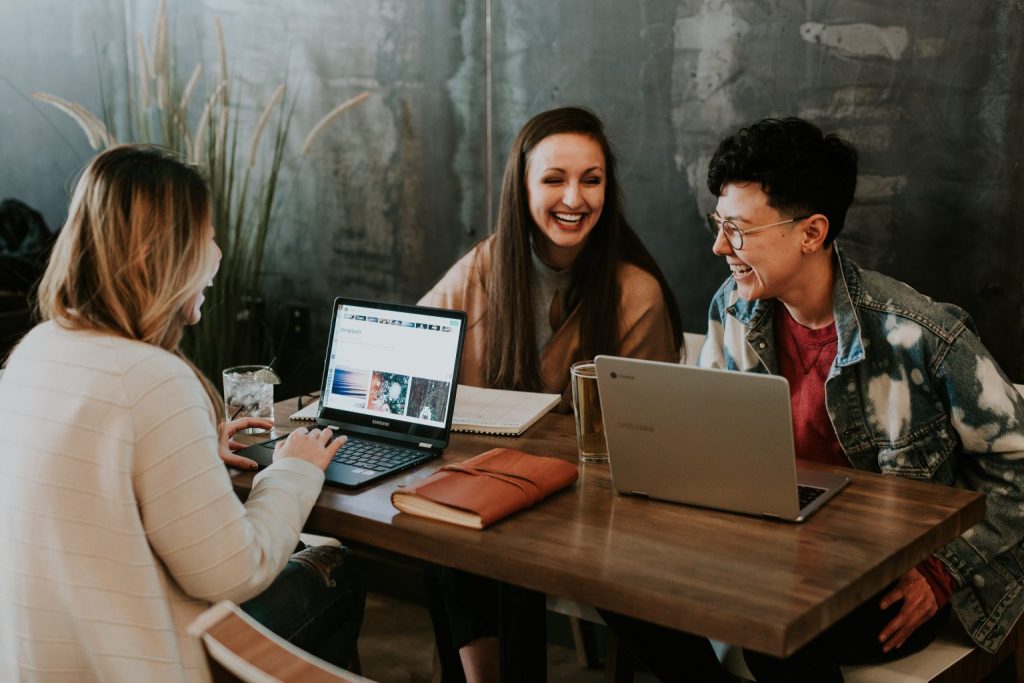 Three friends gathered around table with laptops