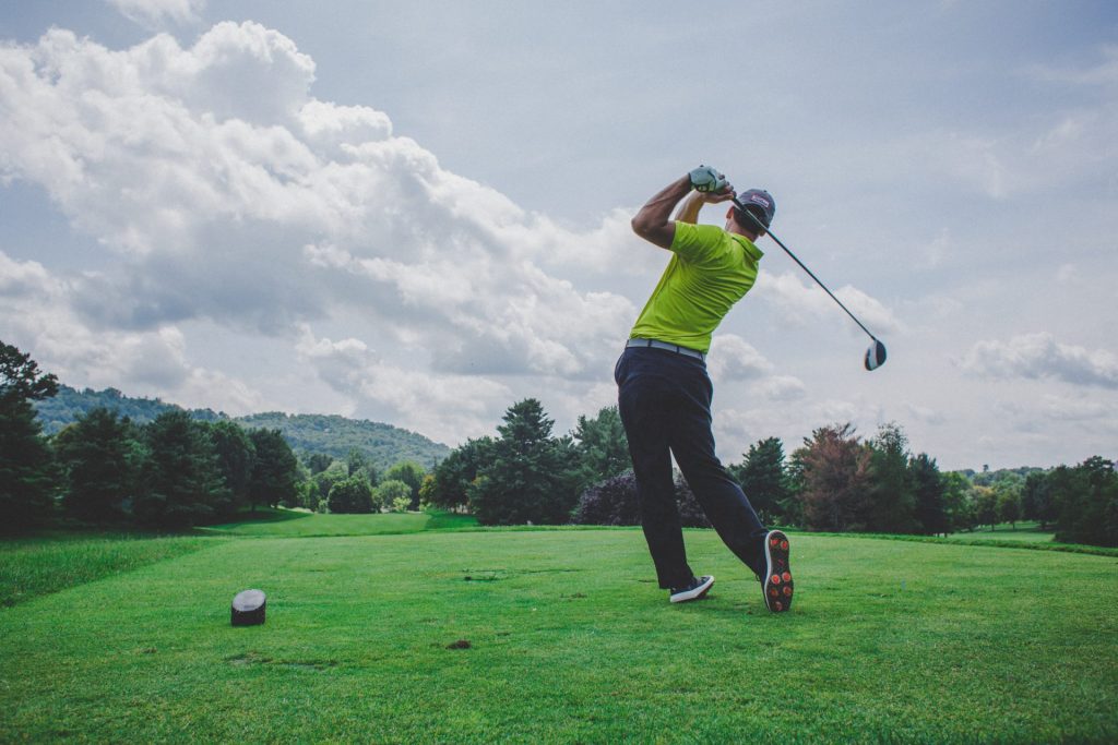 Man swinging golf club on grass