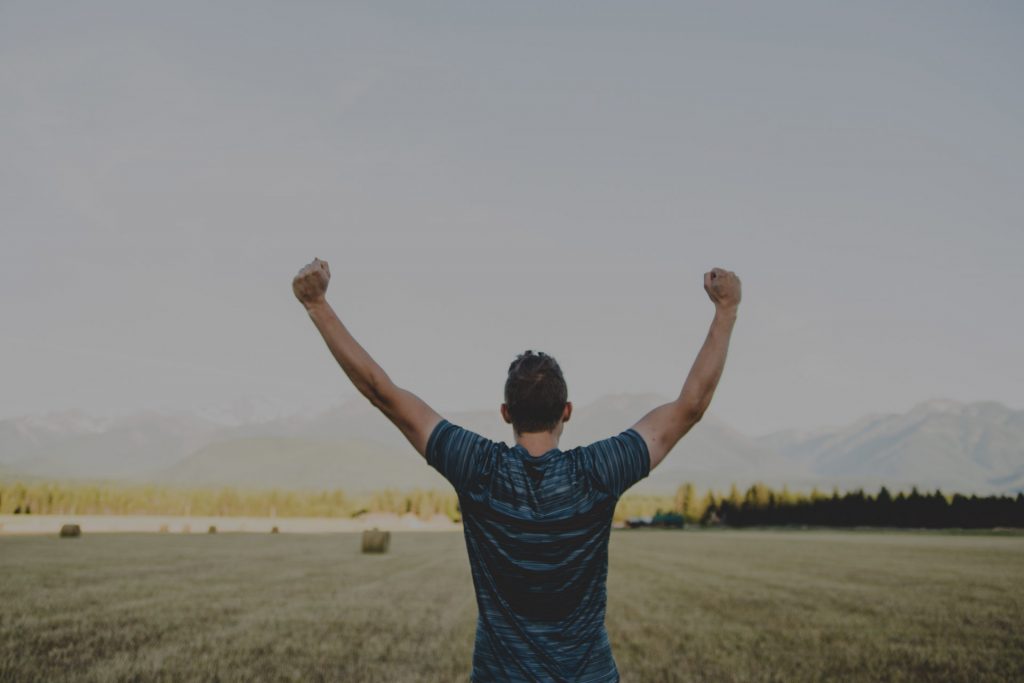 Man with hands up in hay field