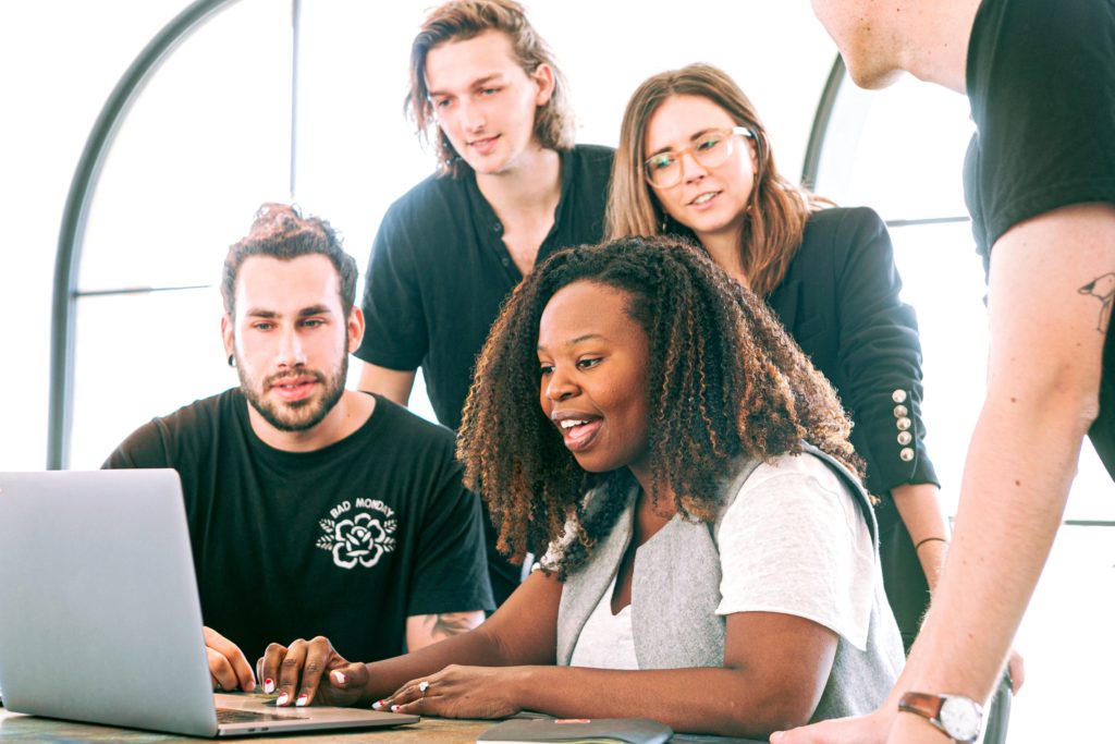 Group of people gathered round laptop working